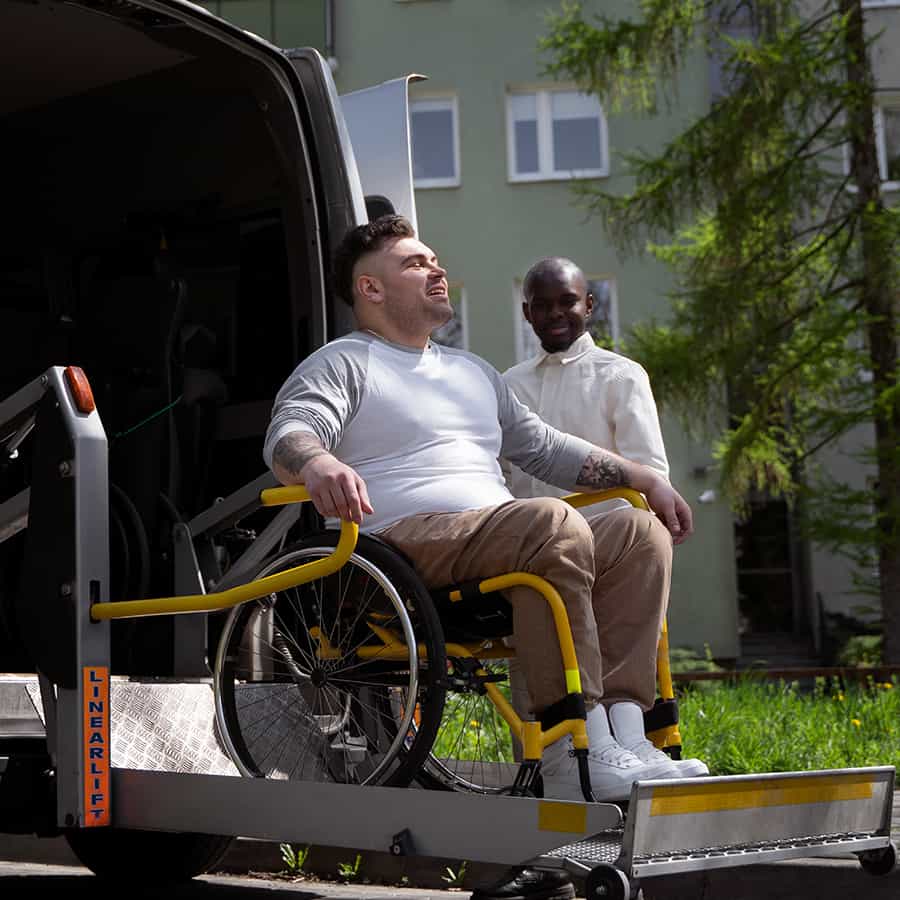 person in a wheelchair being assisted out of a vehicle with a wheelchair lift, promoting mobility and accessibility in an inclusive environment.